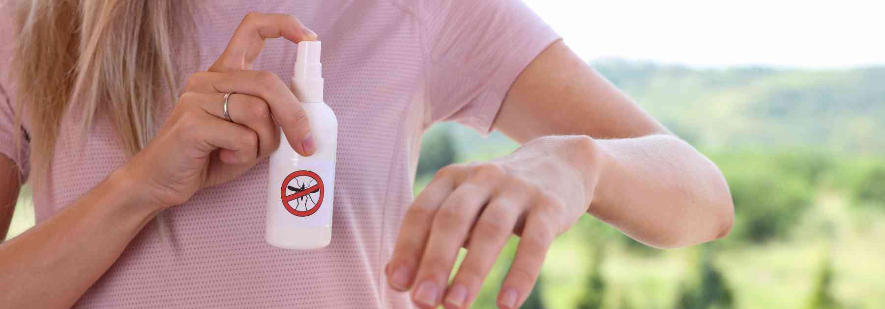 woman spraying insect repellent on her arm