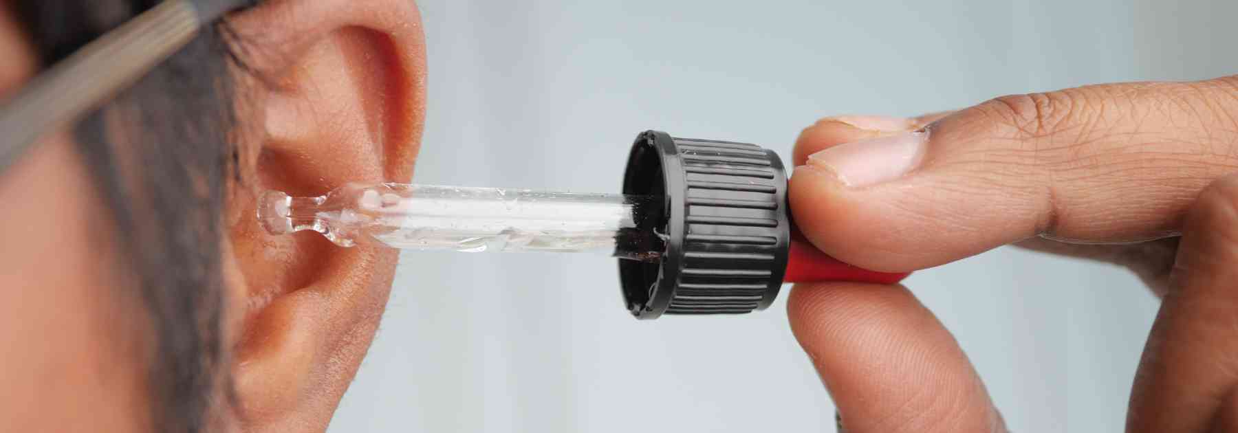 man putting ear drops in ear