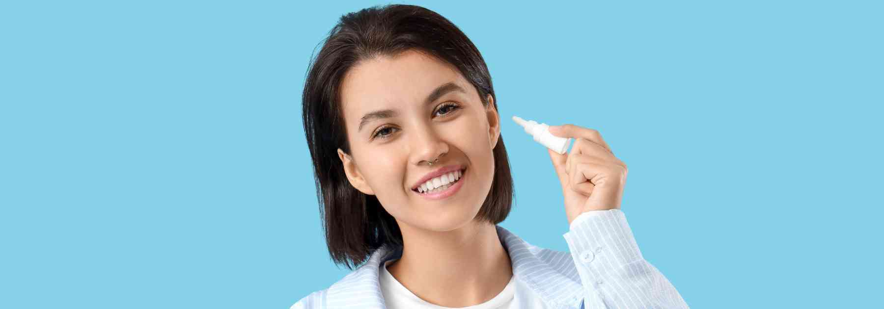 woman holding bottle of ear drops on blue background