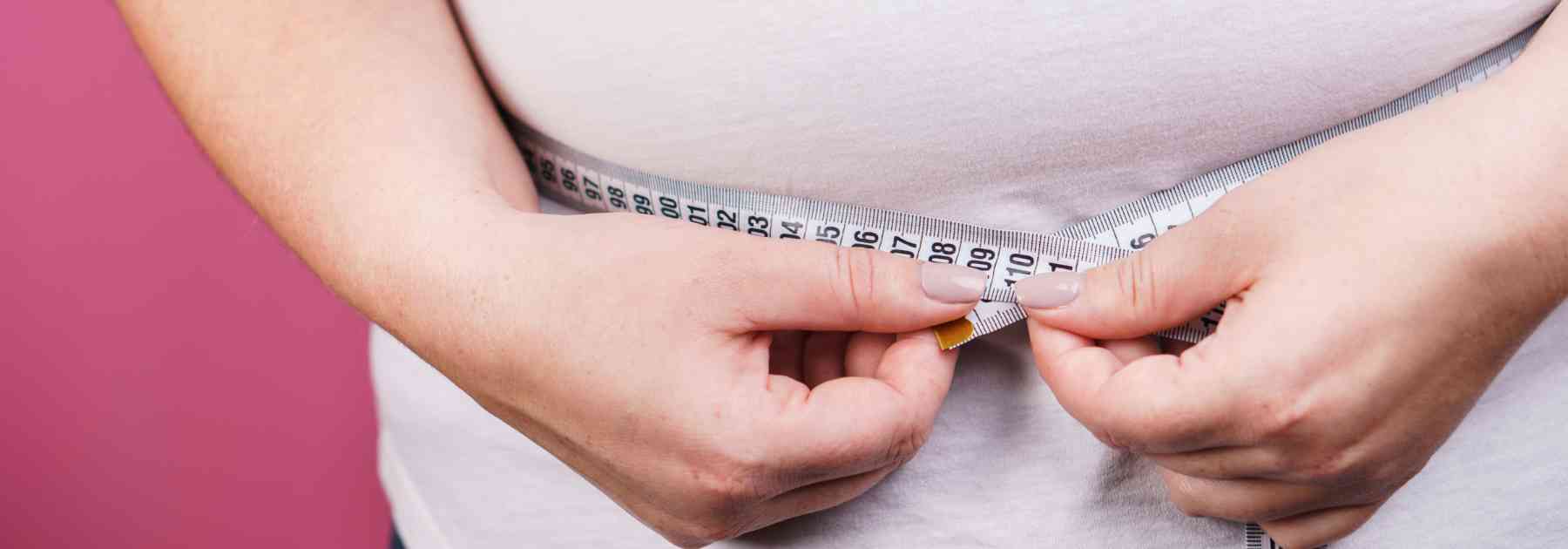 overweight person measuring their waist