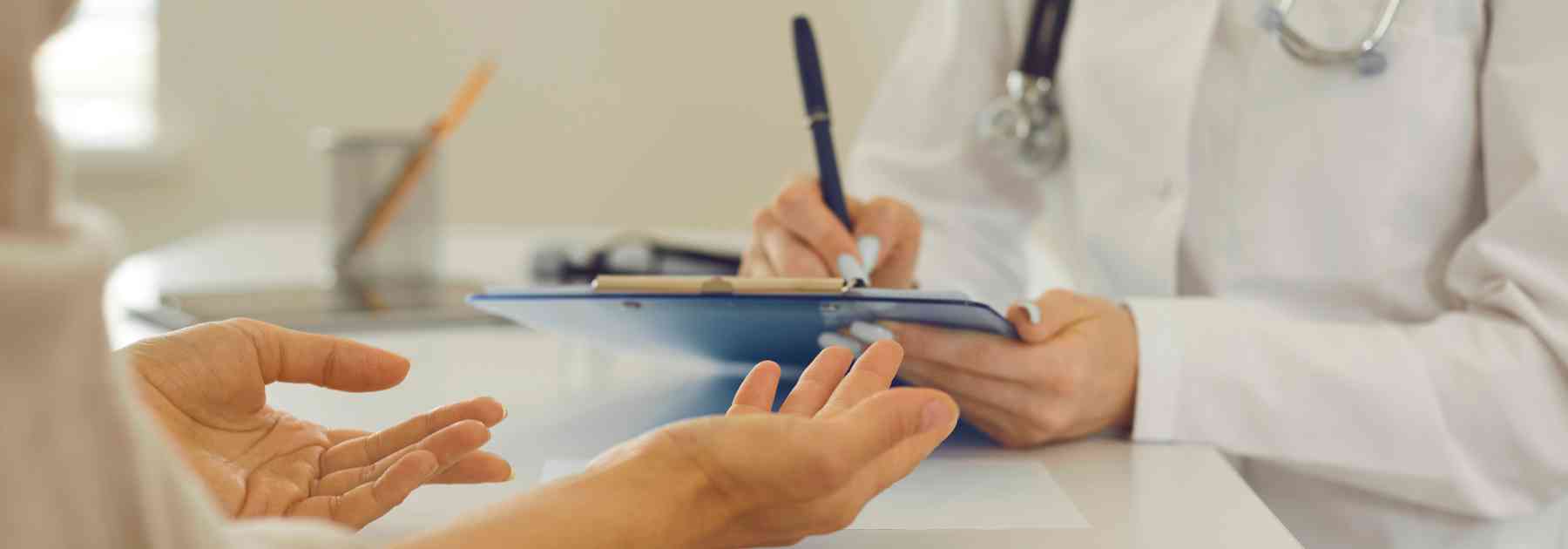 doctor writing on clipboard as patient speaks