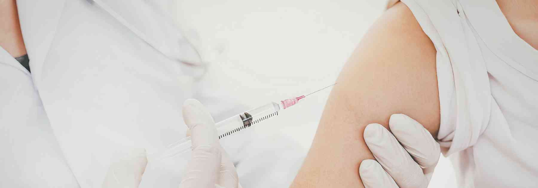 person in white shirt receiving vaccine in arm