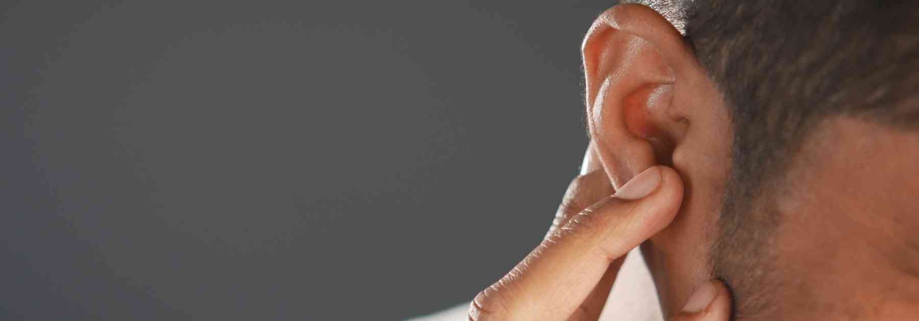 man holding ear in discomfort