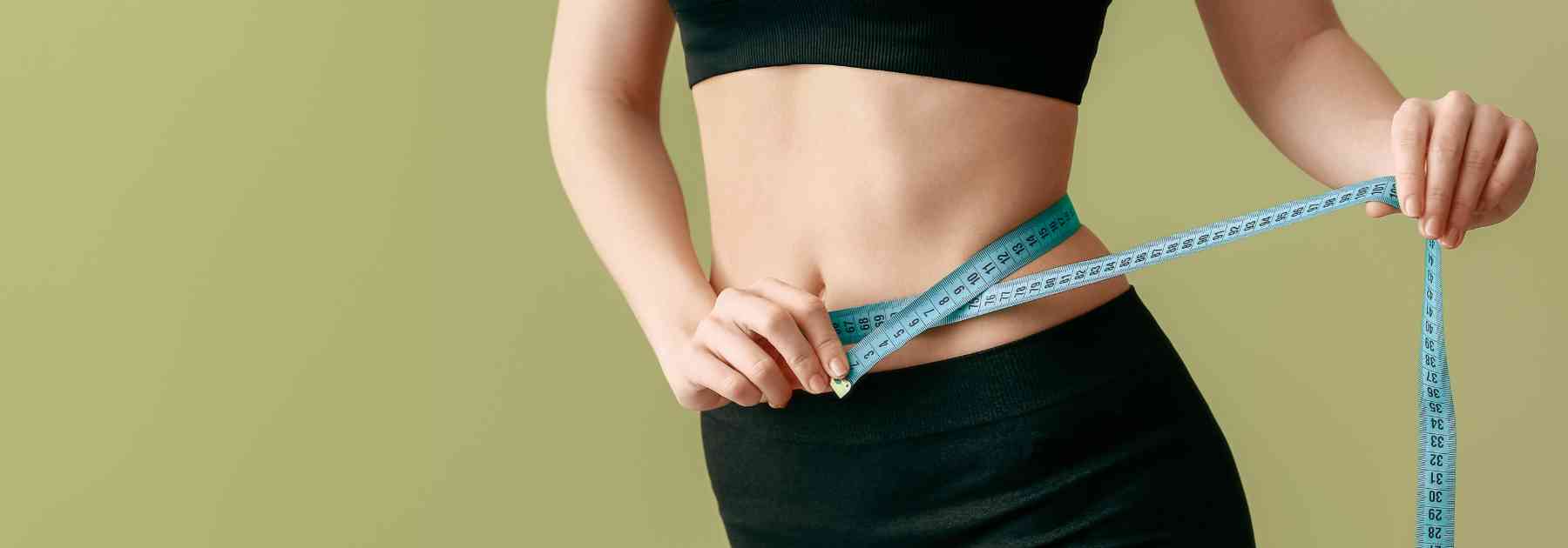 woman in workout gear measuring waist