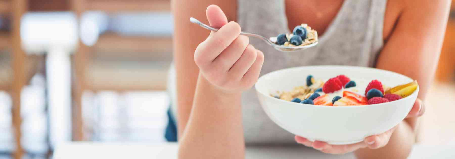 woman eating berries from a bowl