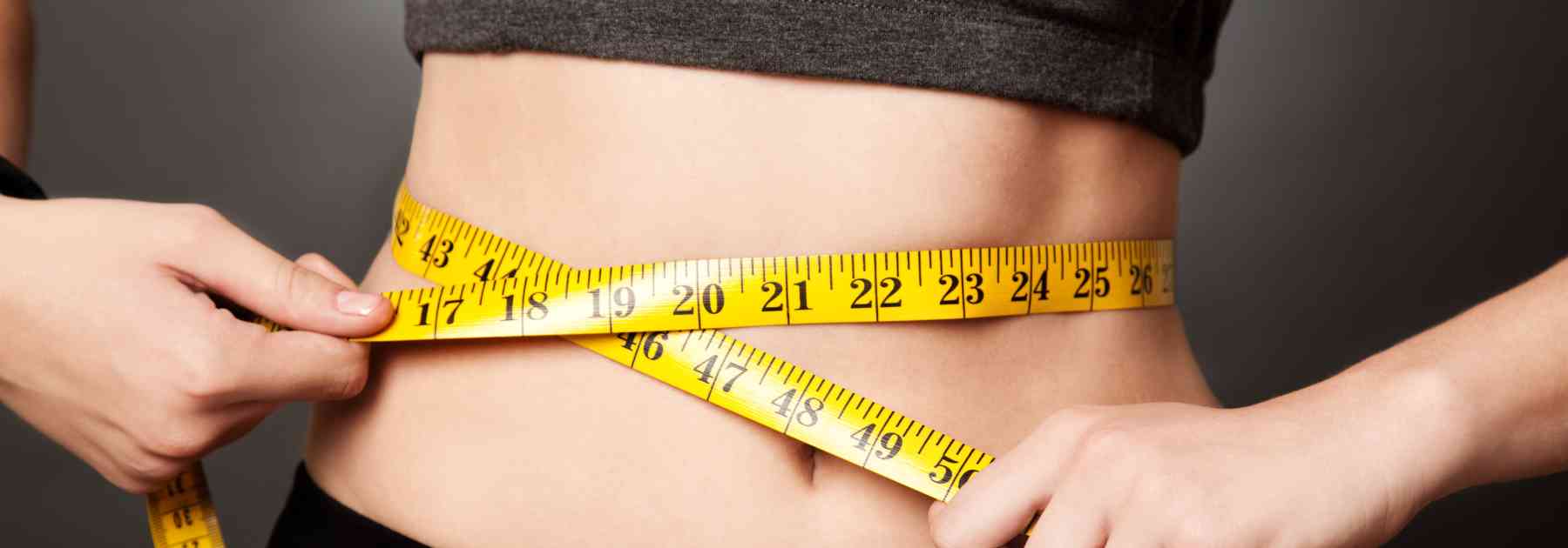 woman in workout gear measuring her waist