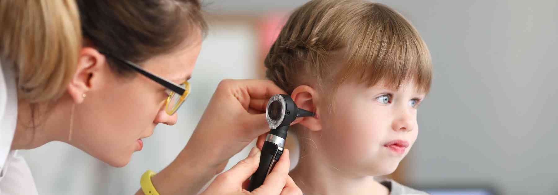 female doctor examining ear of young girl