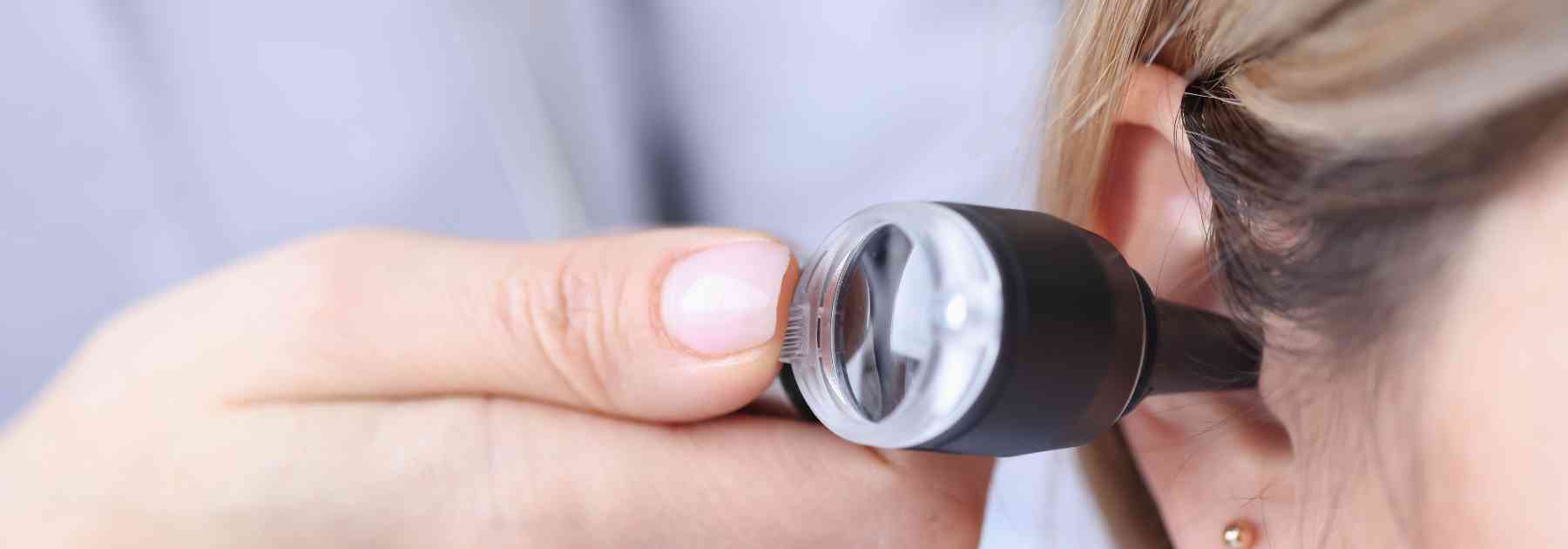 doctor examining ear of female patient