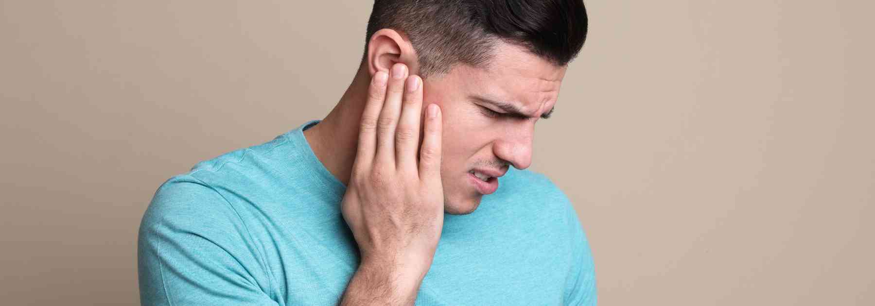 man clutching his ear in discomfort