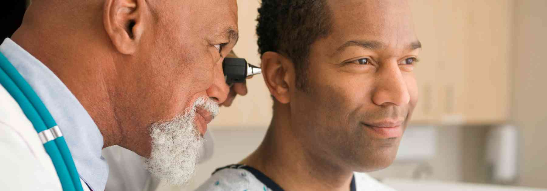 male doctor looking in ear of male patient