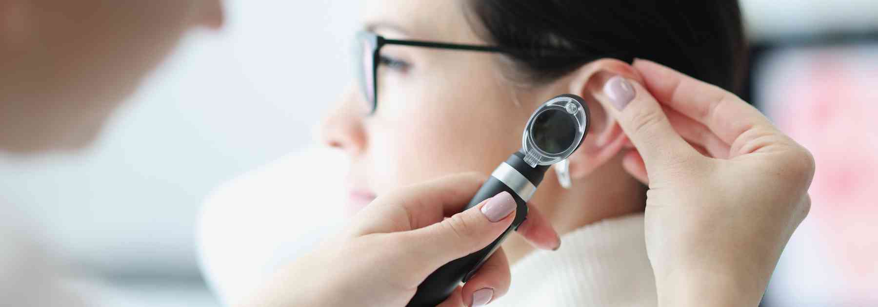 doctor looking in ear of patient wearing spectacles