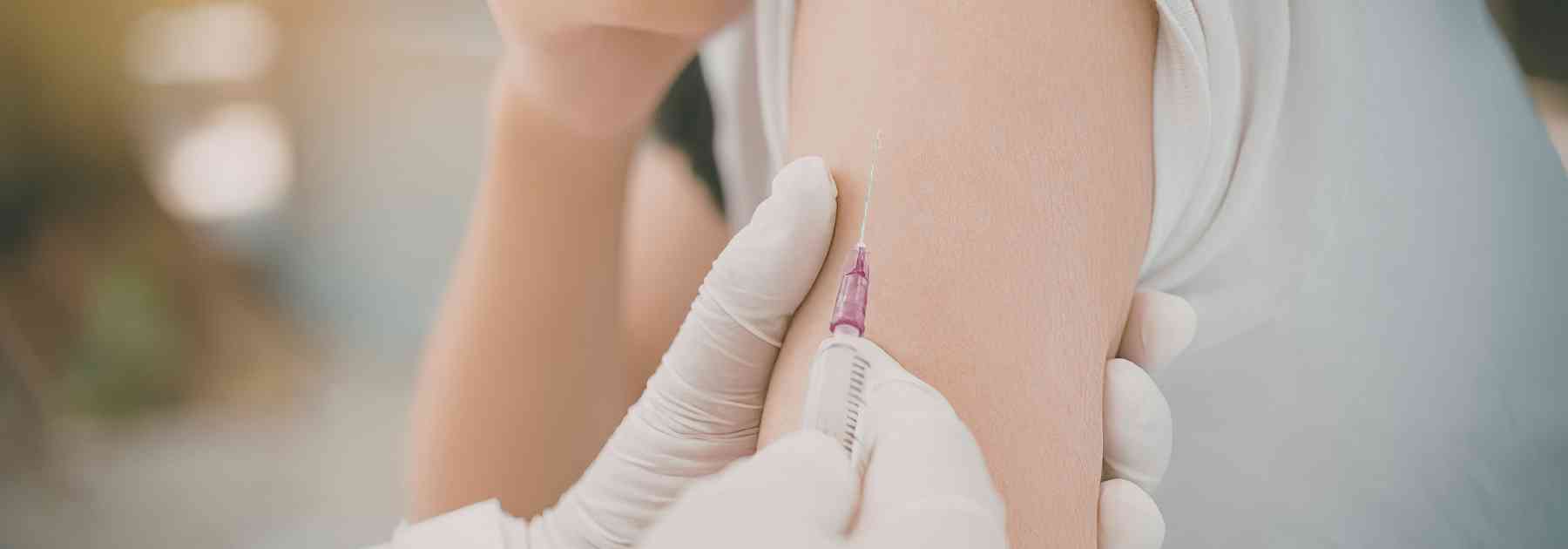 person in white shirt receiving vaccine in arm