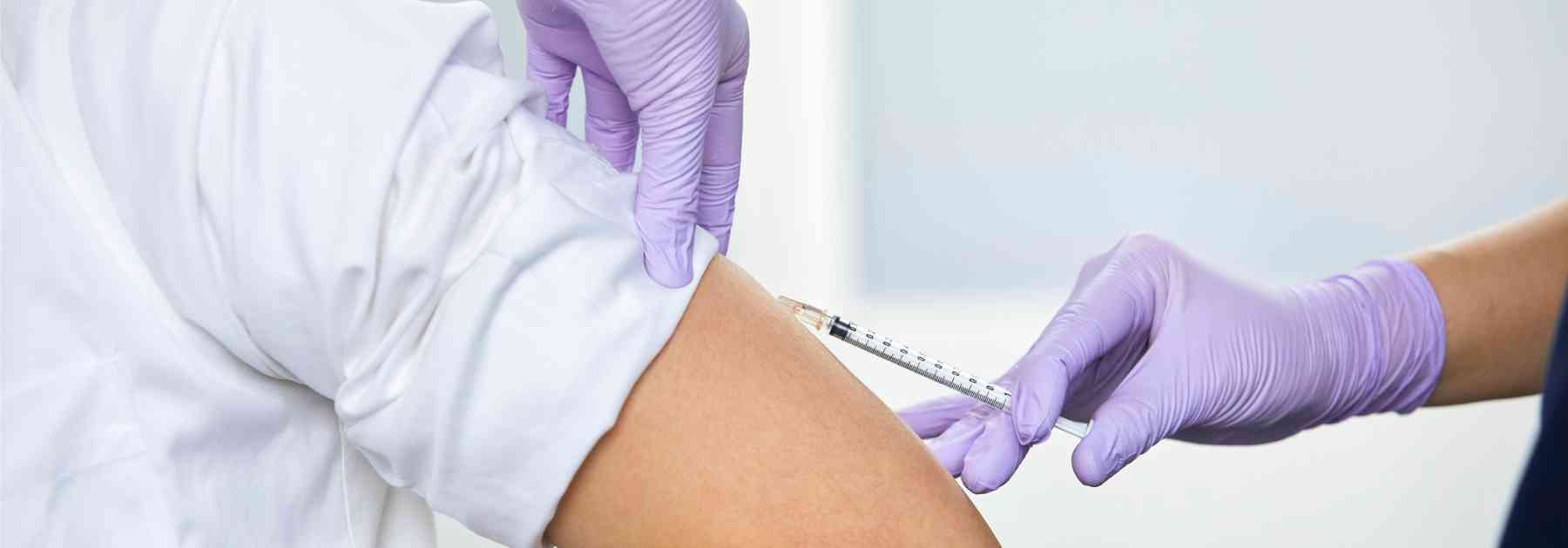 person in white shirt receiving vaccine in arm