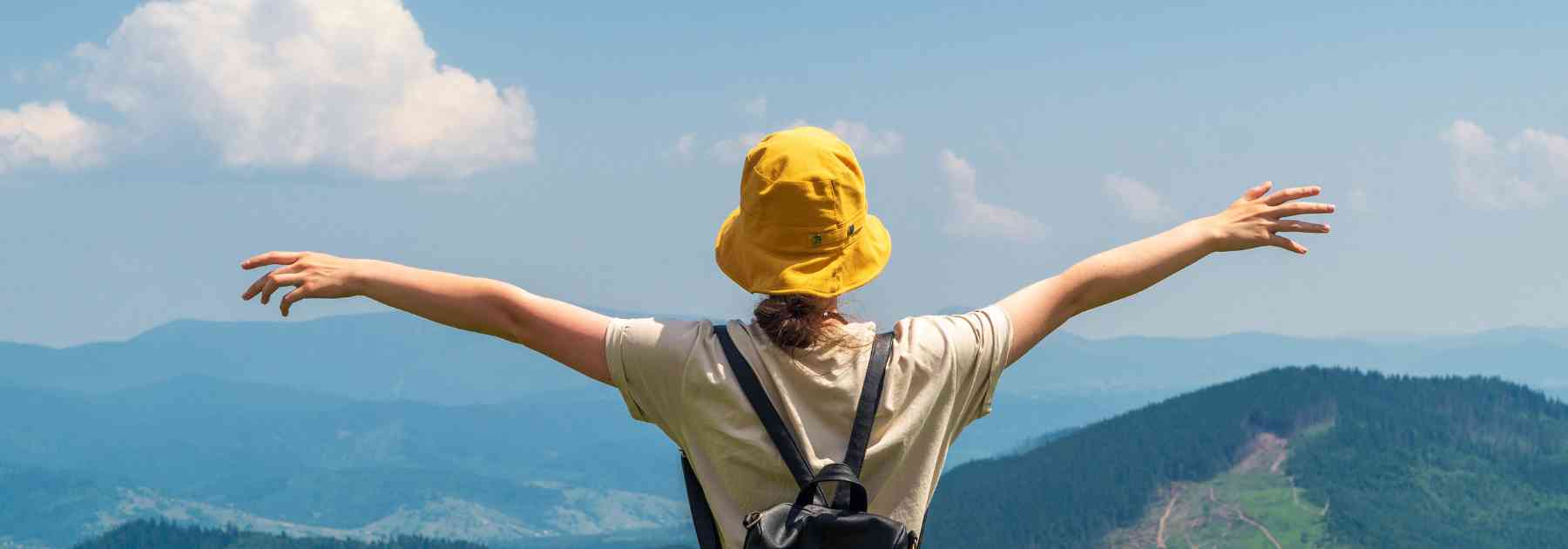 person in yellow hat looking at view of mountains