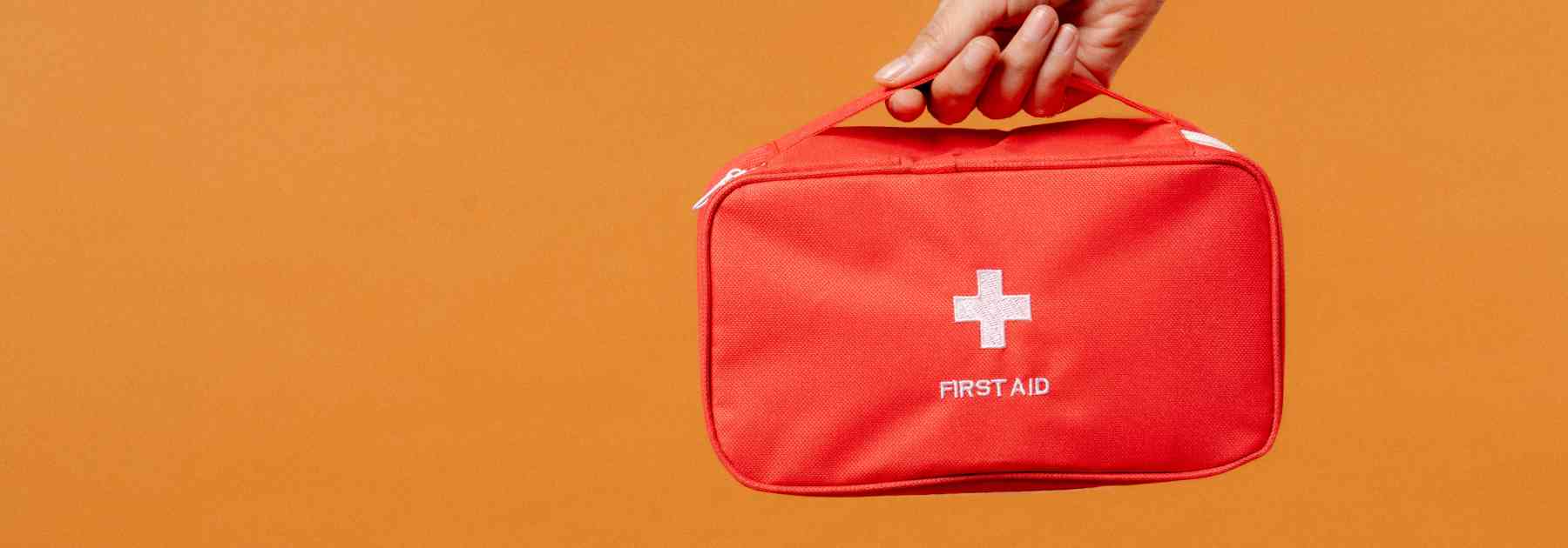 person holding first aid kit on orange background