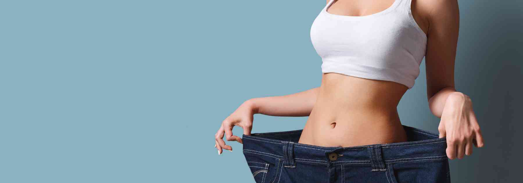 woman wearing jeans too big on blue background