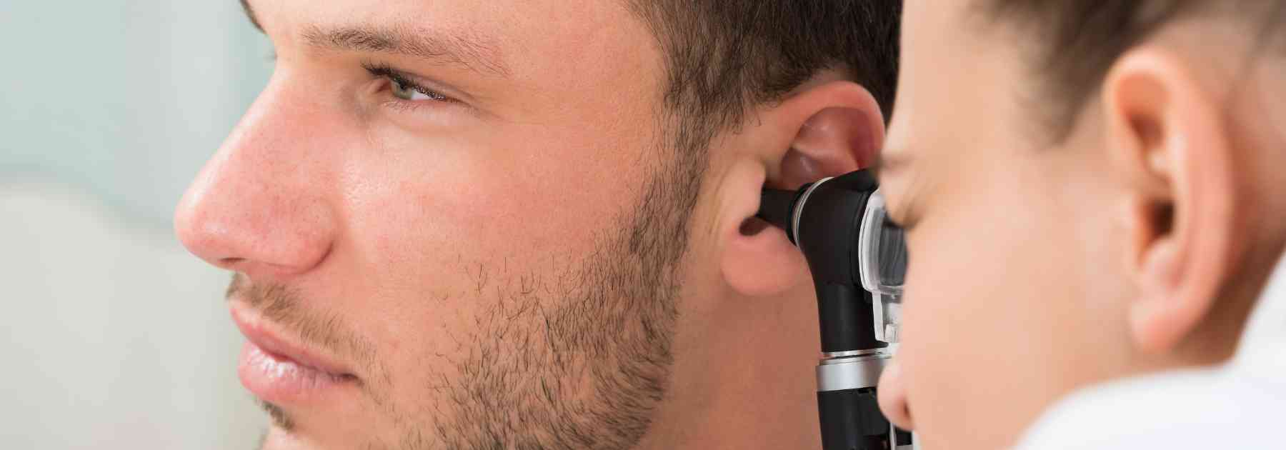 female doctor examining ear of male patient
