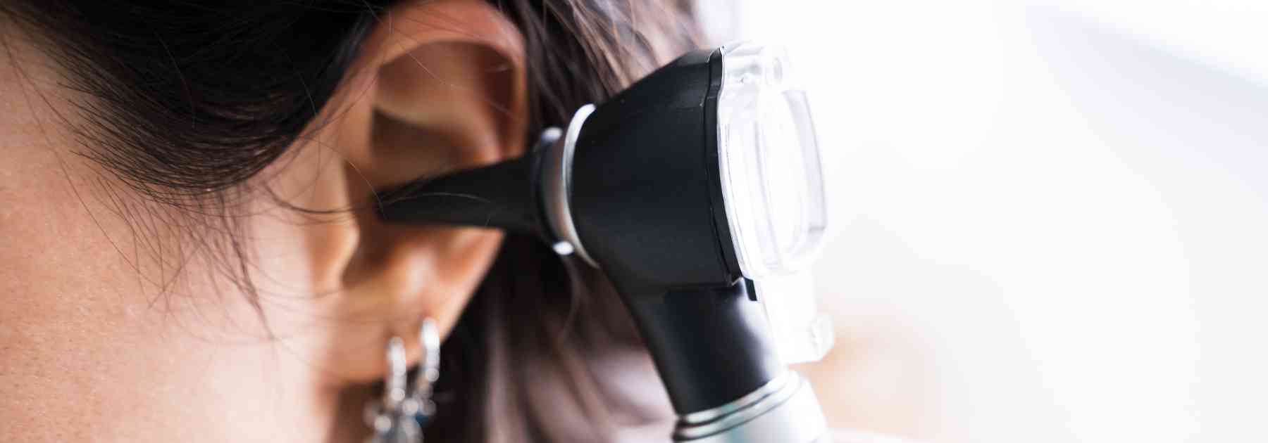 doctor examining ear of female patient