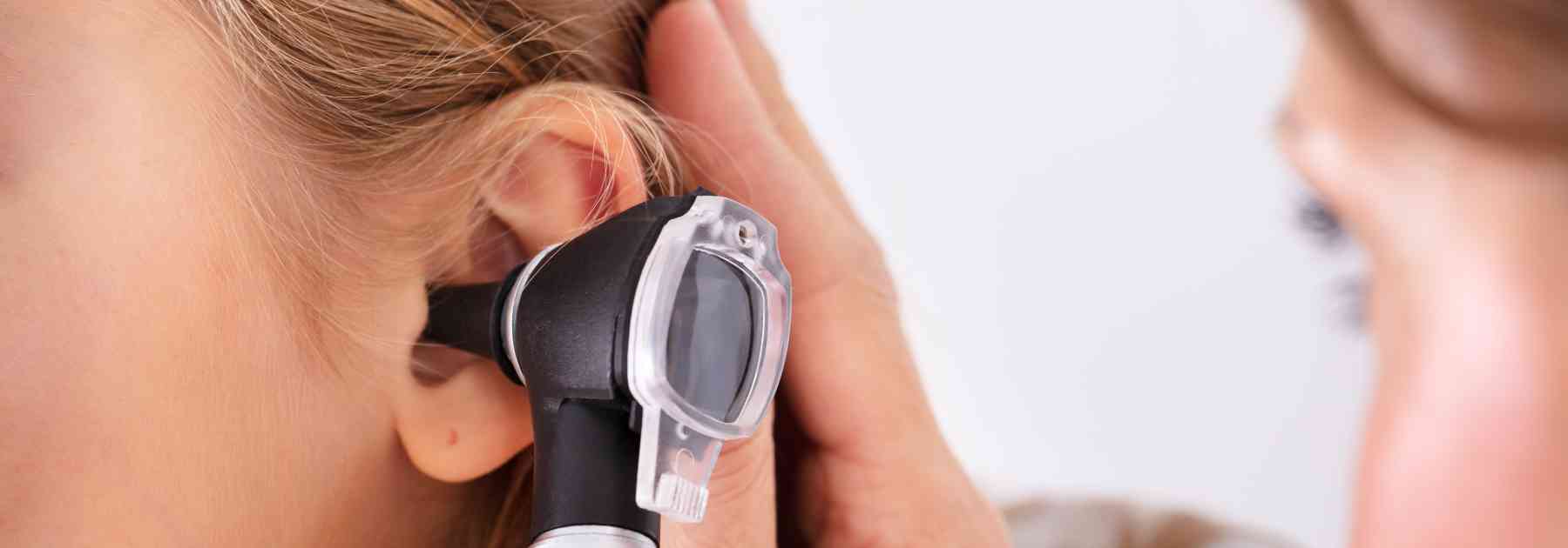 young woman having her ear examined by female doctor