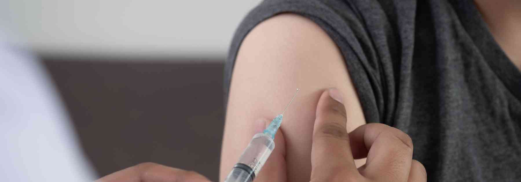 person in grey shirt receiving vaccine in arm