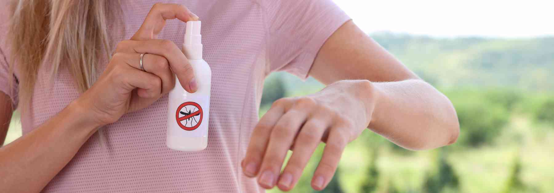 woman spraying insect repellent on her arm
