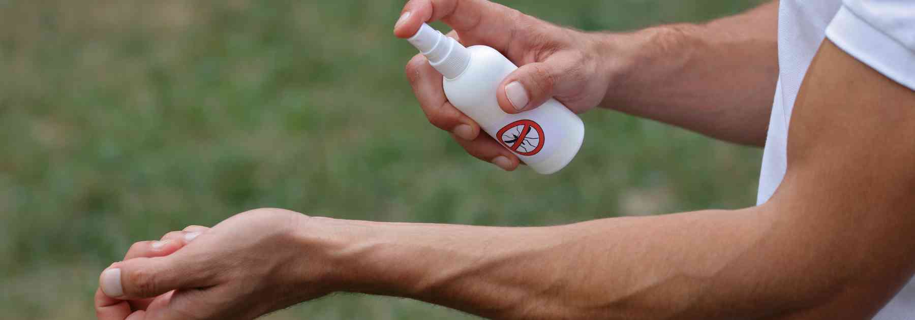 man spraying insect repellent on his arm