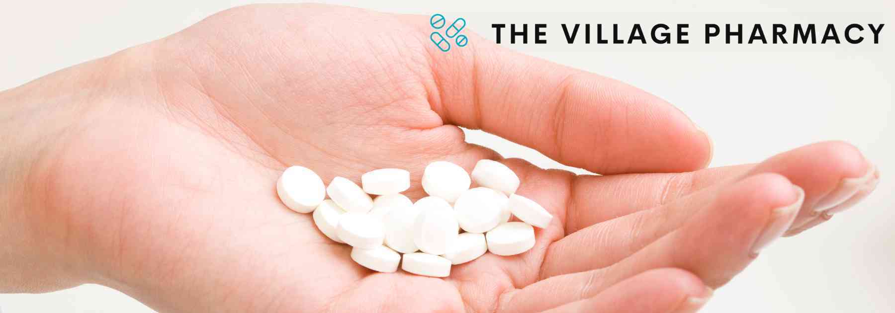 person holding white pills in the palm of their hand