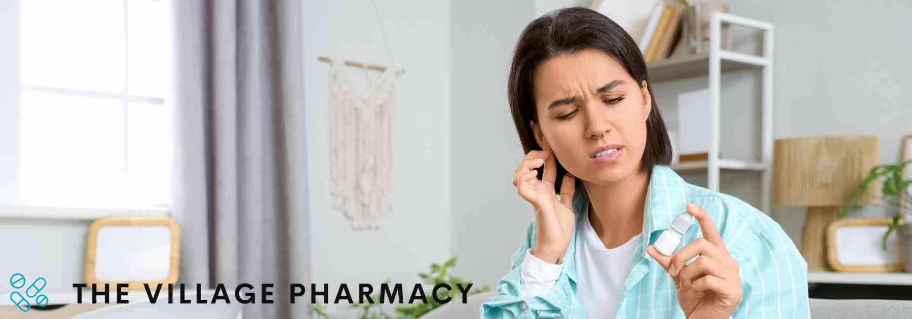 woman in blue jacket holding bottle of ear drops looking confused